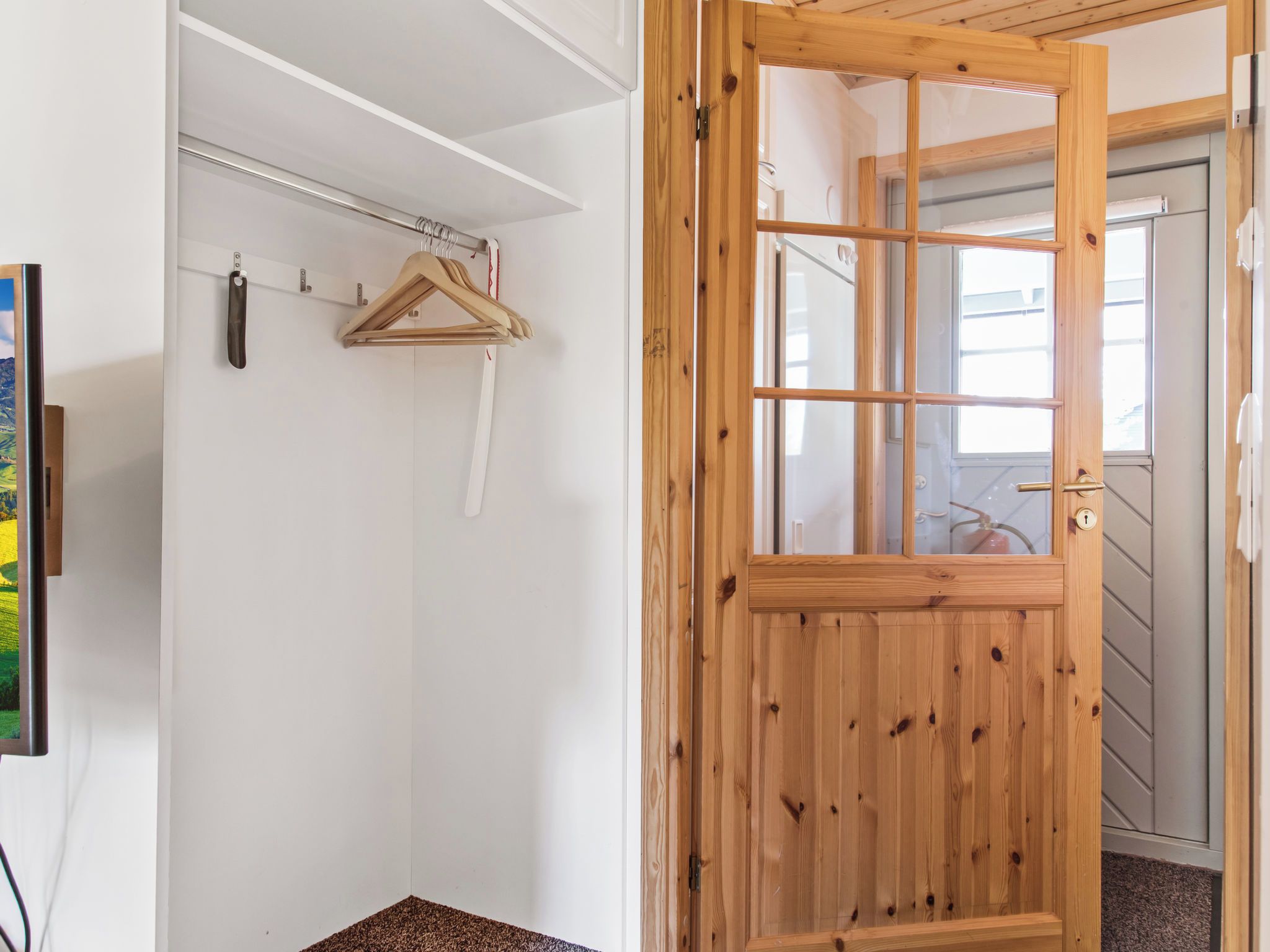 A wooden door with a glass panel, a white closet with a metal rod and wooden hanger, and a view of a staircase.