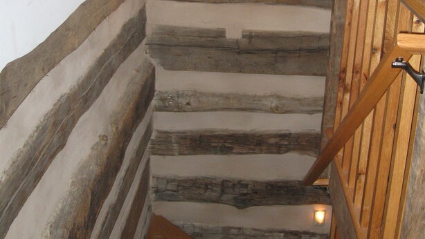 A wooden staircase with a rustic design, a hanging light fixture, and a wooden railing. - Tavern River Cabin, Historical,  Riverfront, Log, Hottub, Large Stone Fireplace (Luray)