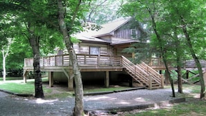 A wooden cabin with a deck and stairs, surrounded by trees. - Tavern River Cabin, Historical,  Riverfront, Log, Hottub, Large Stone Fireplace (Luray)