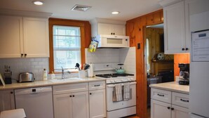 Une cuisine avec des meubles blancs, une cuisinière, un four à micro-ondes et un lave-vaisselle.
