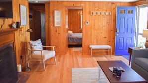 Une pièce chaleureuse avec des murs en bois, une porte bleue, un lit, une chaise, un canapé et une table basse.