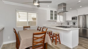 A modern kitchen with white cabinetry, a stainless steel refrigerator, and a ceiling fan. - Oceanfront South Mission Beach Vacation Rental on the Sand 2737 (San Diego)