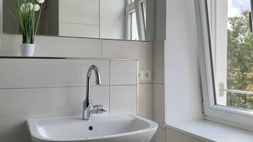 A bathroom with a white sink, wooden vanity, and a window with a view of trees.