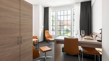 Une chambre d’hôtel moderne dotée d’un coin repas, de grandes fenêtres et d’une vue sur l’extérieur.