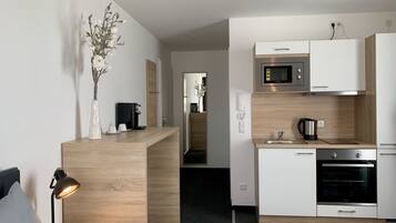 A modern kitchen with a wooden countertop, a coffee machine, a kettle, and a microwave.