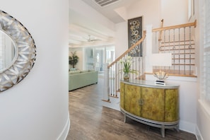 Staircase leads to an upper level, featuring a decorative cabinet and a green sofa in a stylish living area.