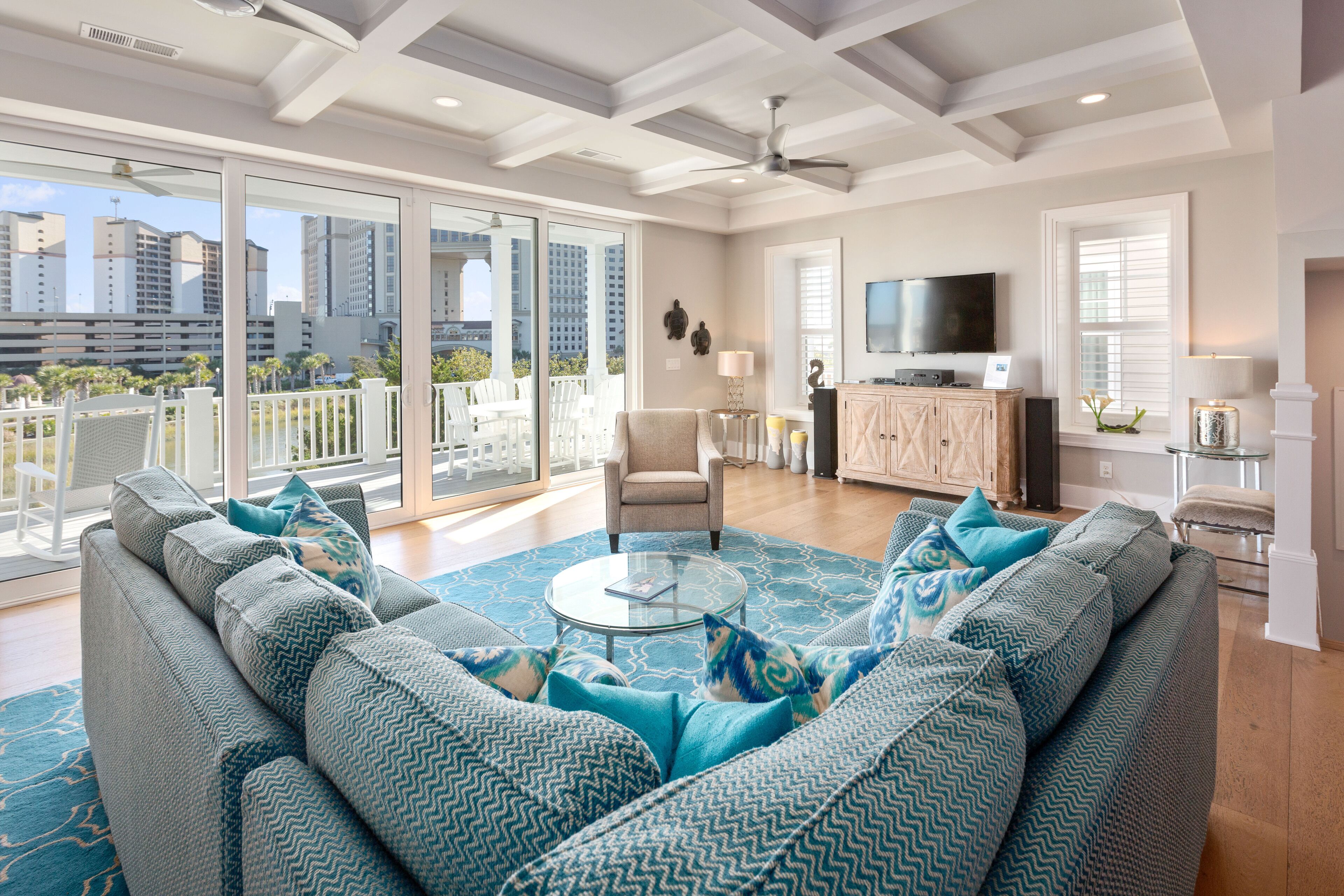 A spacious living room with a large sofa, a glass coffee table, and a view of the city through large sliding doors.
