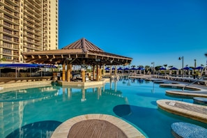 Relax by the resort pool surrounded by smaller pools and sun loungers under a central gazebo.