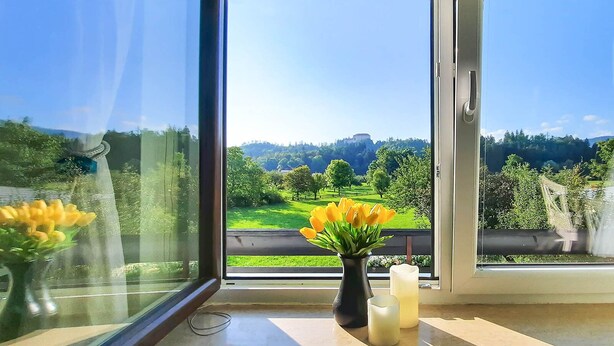 A room with a large window offering a view of a green landscape and a distant hill.