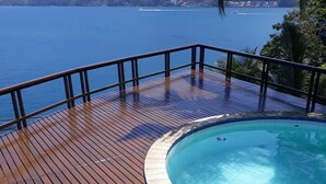 A wooden deck with a pool, overlooking a body of water and hills. - ANGRA DOS REIS. CONDITION PORTOGALO RJ CASA DO GUGU  (ANGRA DOS REIS)
