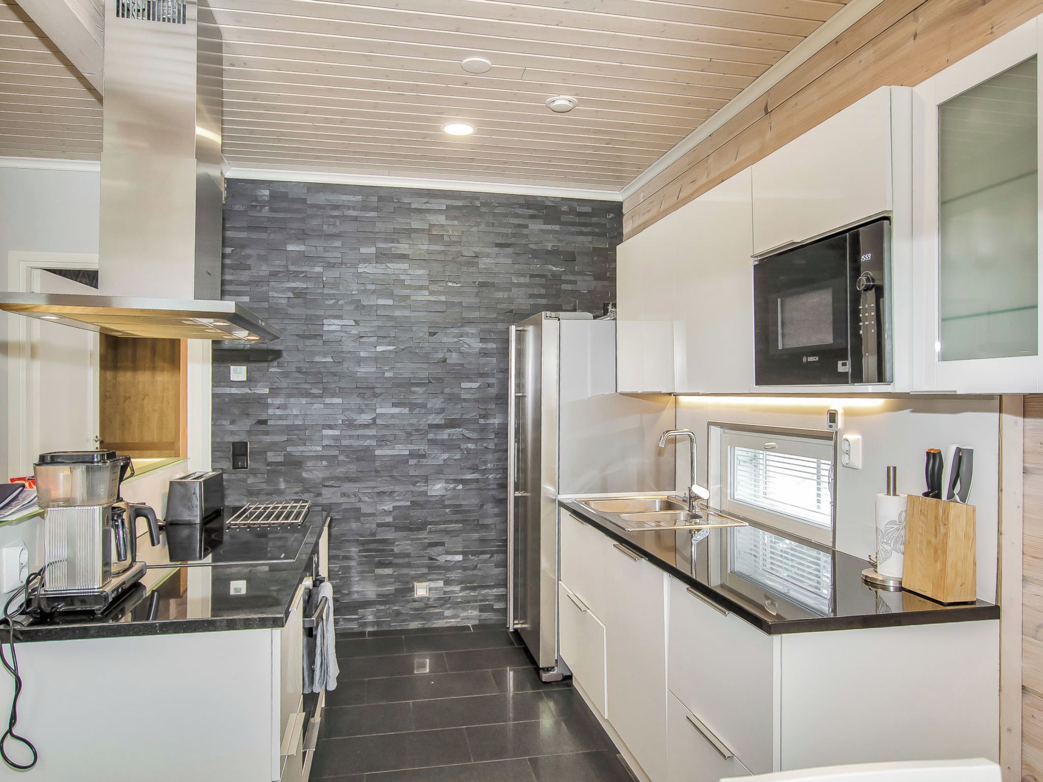 Una cocina moderna con salpicadero de piedra, electrodomésticos de acero inoxidable y microondas integrado.