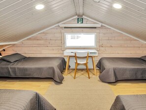 Une chambre confortable située sous les toits, avec deux lits, un bureau et un ordinateur.