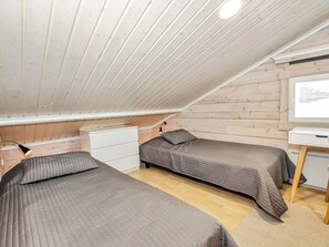 A small, cozy attic bedroom with two beds, a desk, and a whiteboard.