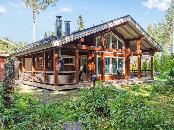 A cabin with a wooden deck, large windows, and a chimney. - Villa utu by Interhome (Lieksa)
