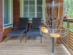 A wooden deck with two lounge chairs and a metal disc golf basket.