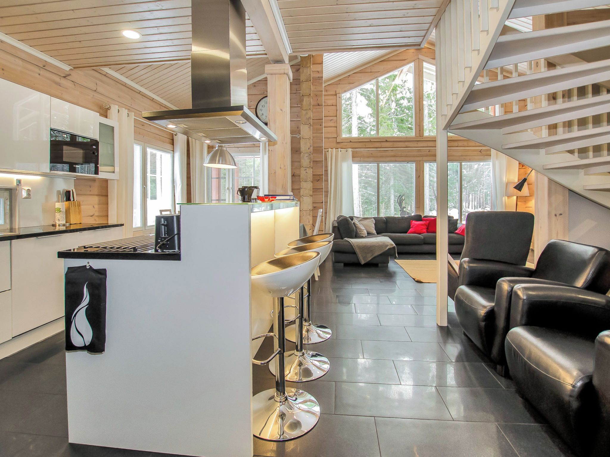 A modern kitchen with a central island, bar stools, and a dining area with a sofa and chairs.