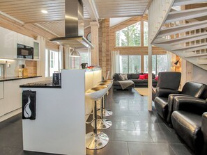 Una cocina moderna con una isla central, taburetes de bar y un comedor con sofá y sillas.