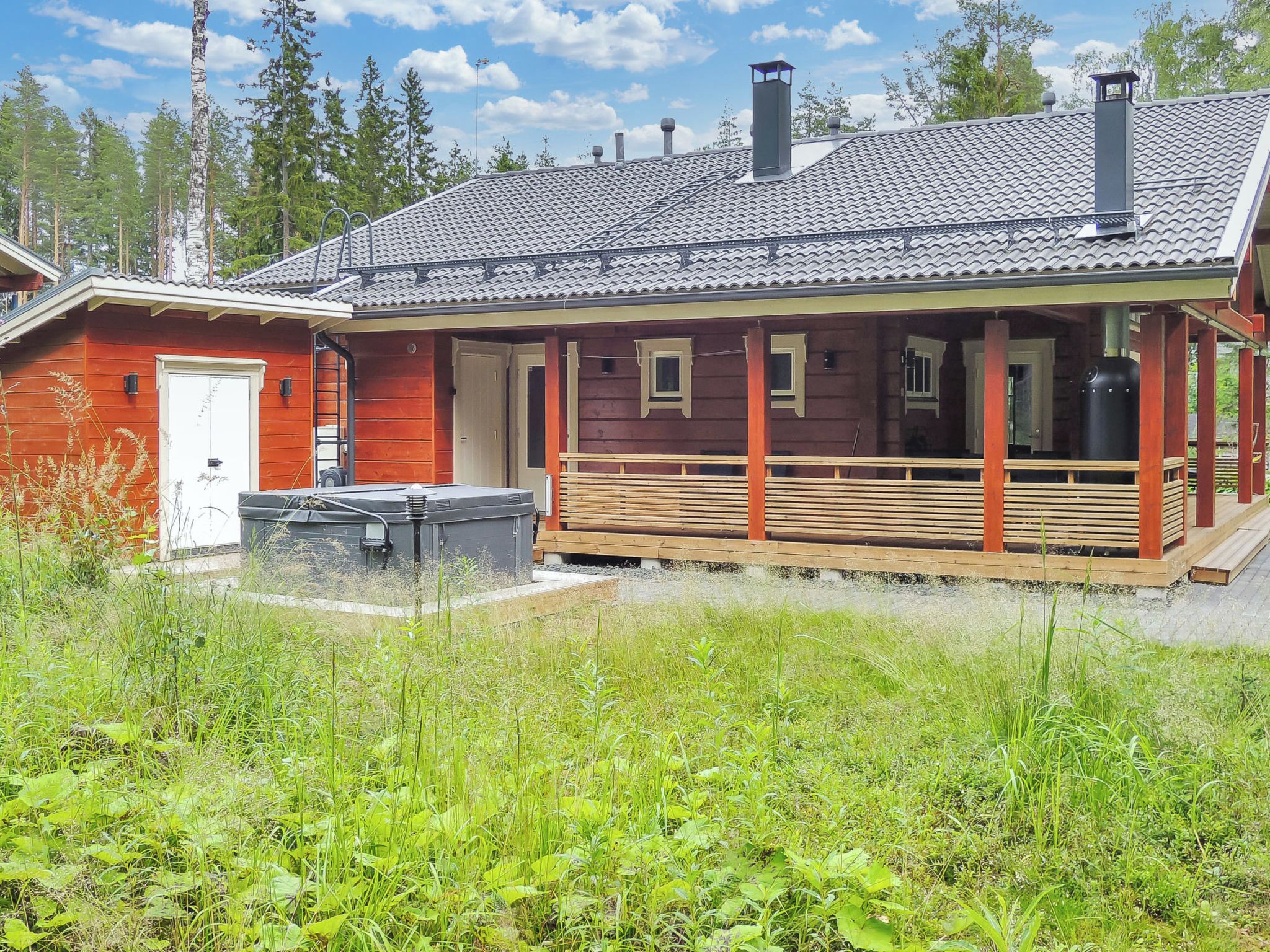 A cabin with a covered porch, a small deck, and a chimney.