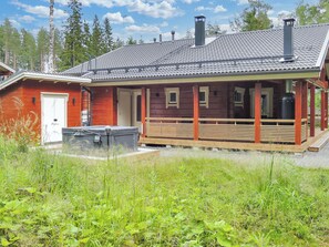 A cabin with a covered porch, a small deck, and a chimney.