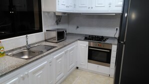 A kitchen with white cabinets, a stainless steel sink, a microwave, an oven, and a black refrigerator. - Atlantic view with free car and bike.  (Gaula)