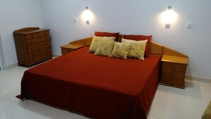 A bedroom with a large bed, wooden nightstands, a dresser, and two wall-mounted lights. - Atlantic view with free car and bike.  (Gaula)
