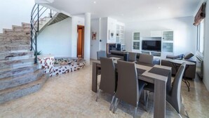 Un salon moderne comprenant un coin repas, un escalier et une cuisine.