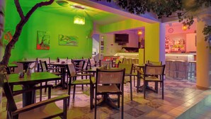 A restaurant with a green wall, wooden tables and chairs, a bar area, and a television. - Spacious apartment just 2 min walk from the beach! (Plakias)