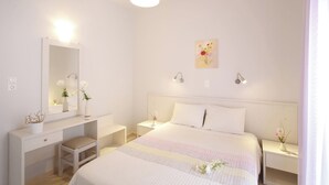 A bedroom with a bed, bedside tables, a mirror, and a dresser. - Spacious apartment just 2 min walk from the beach! (Plakias)