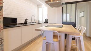 Una cocina moderna con una isla central, armarios blancos y un microondas negro.