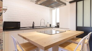 Una cocina moderna con una isla central, salpicadero de azulejos blancos y un amplio ventanal.