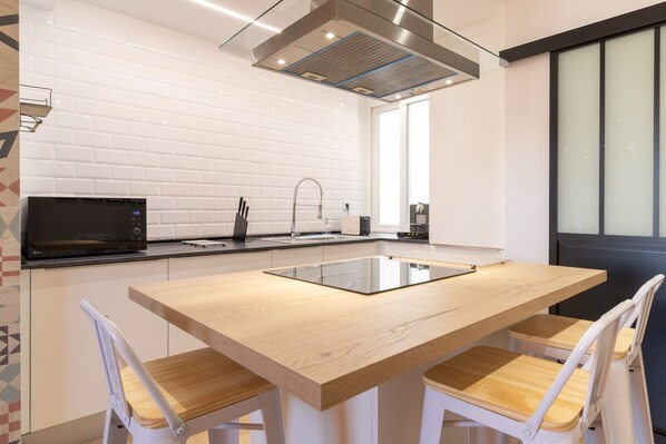 A modern kitchen with a central island, white tiled backsplash, and a large window.