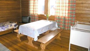 A cabin with a wooden interior, a bed, a table with a tablecloth, a bench, a TV, and plaid curtains. - Herkkola by Interhome (Taivalkoski)