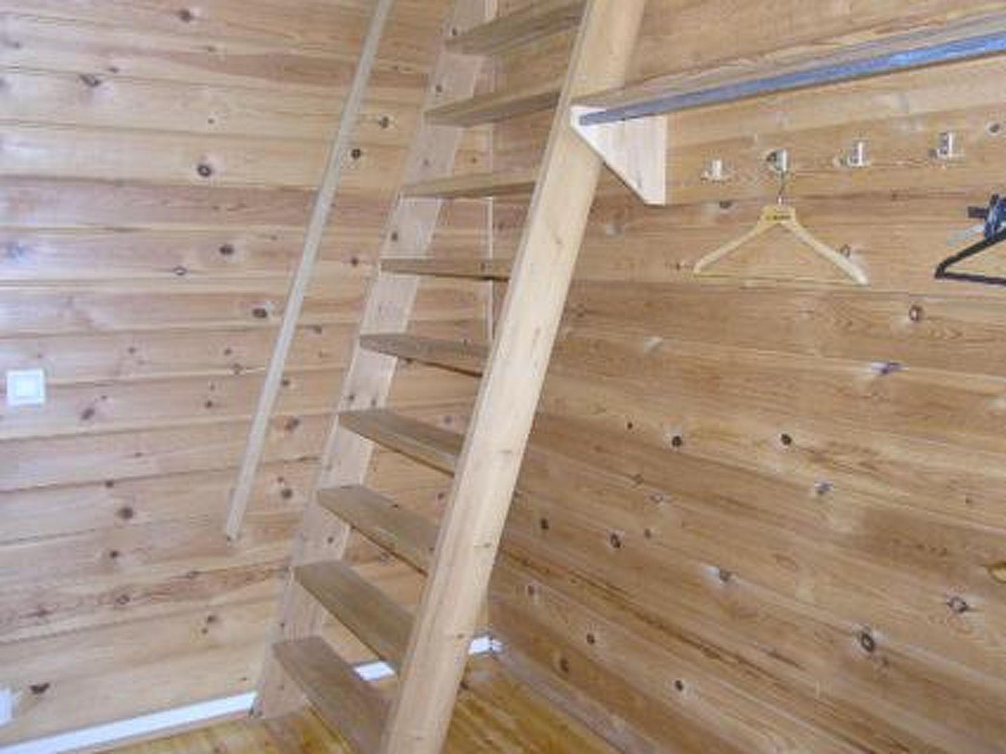 A wooden interior with a sloped ceiling and a metal railing.