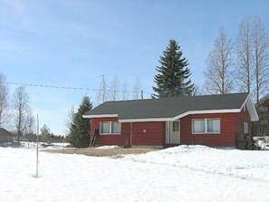 A red single-story house with a dark roof, surrounded by snow, with bare trees and power lines in the background. - Herkkola by Interhome (Taivalkoski)