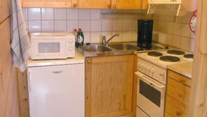 A compact kitchen with wooden cabinets, a microwave, a coffee maker, and a stove. - Herkkola by Interhome (Taivalkoski)