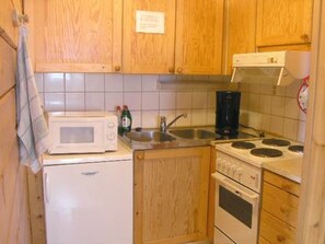 Una cocina compacta con armarios de madera, microondas, cafetera y estufa.