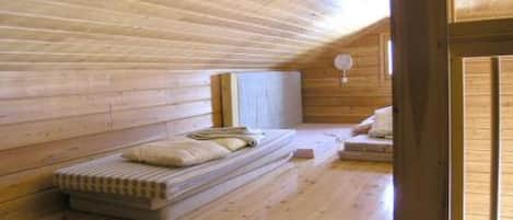 Een houten interieur met een stapelbed, een tafeltje en een raam.