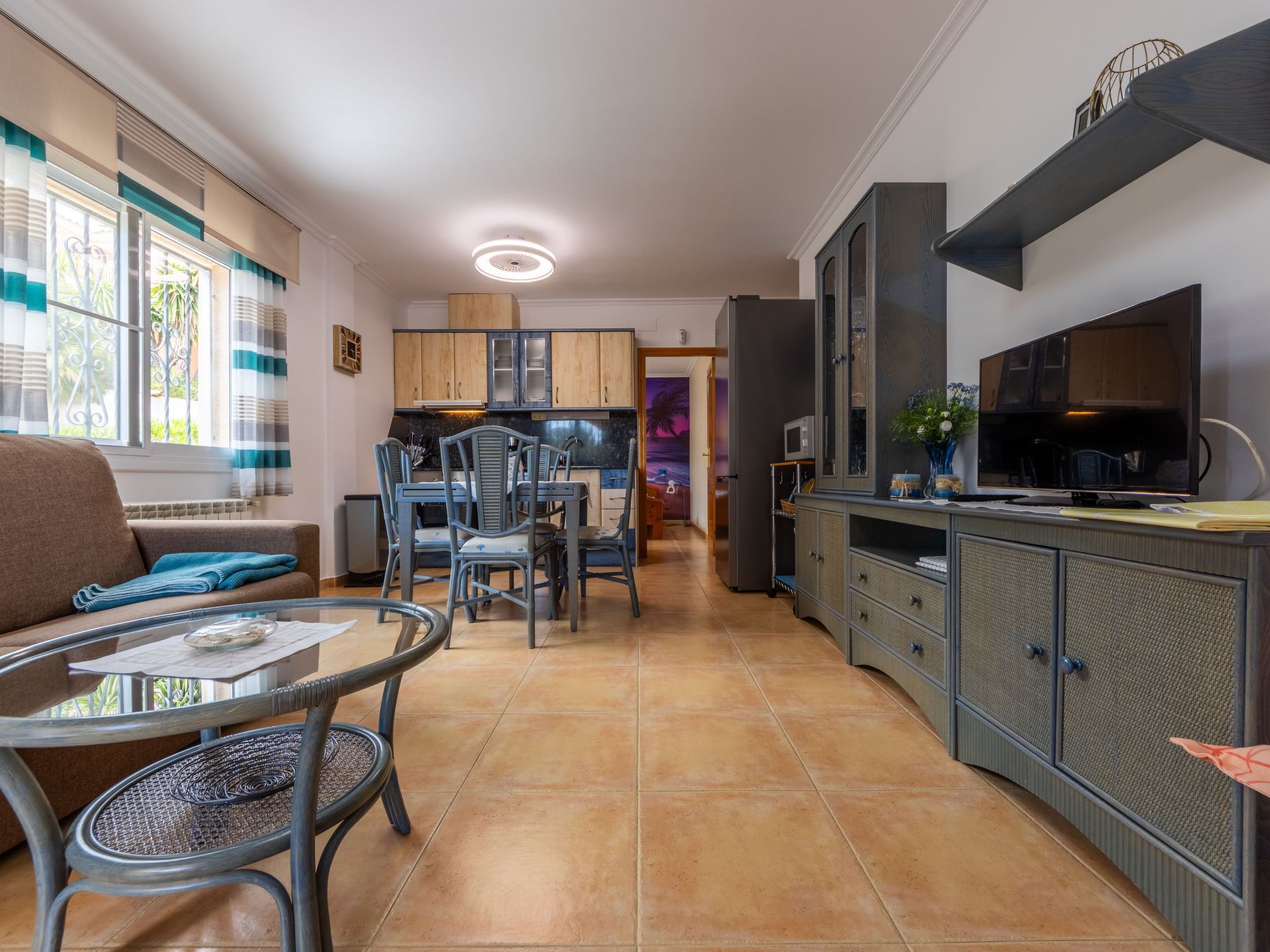Una cocina moderna con zona de comedor, que incluye una isla de cocina, horno empotrado y un televisor de pantalla plana grande.