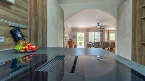 A modern kitchen with a central island, a dining area with a view, and a ceiling fan.