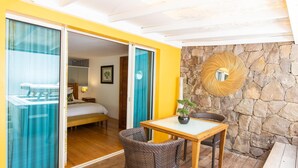 A room with a bed, a table with chairs, a potted plant, and a stone wall with a circular mirror. - Lodge Freedom      . (La Grande Saline)