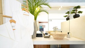 A modern bathroom with a large sink, a mirror, a wooden bath mat, and a potted plant. - Lodge Freedom      . (La Grande Saline)