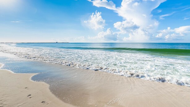 Une plage avec un ciel dégagé et des vagues.