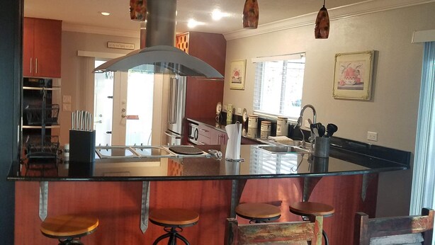 A kitchen with a central island, bar stools, and pendant lighting. - Bamboo Beach House! (Redington Beach)