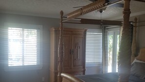 A bedroom with a four-poster bed, wooden flooring, and a ceiling fan. - Bamboo Beach House! (Redington Beach)