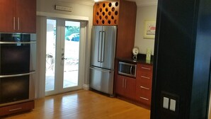 A modern kitchen with wooden cabinets, stainless steel appliances, and a large refrigerator. - Bamboo Beach House! (Redington Beach)