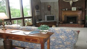 Een gezellige woonkamer met een bank, een houten salontafel, een televisie en een open haard.