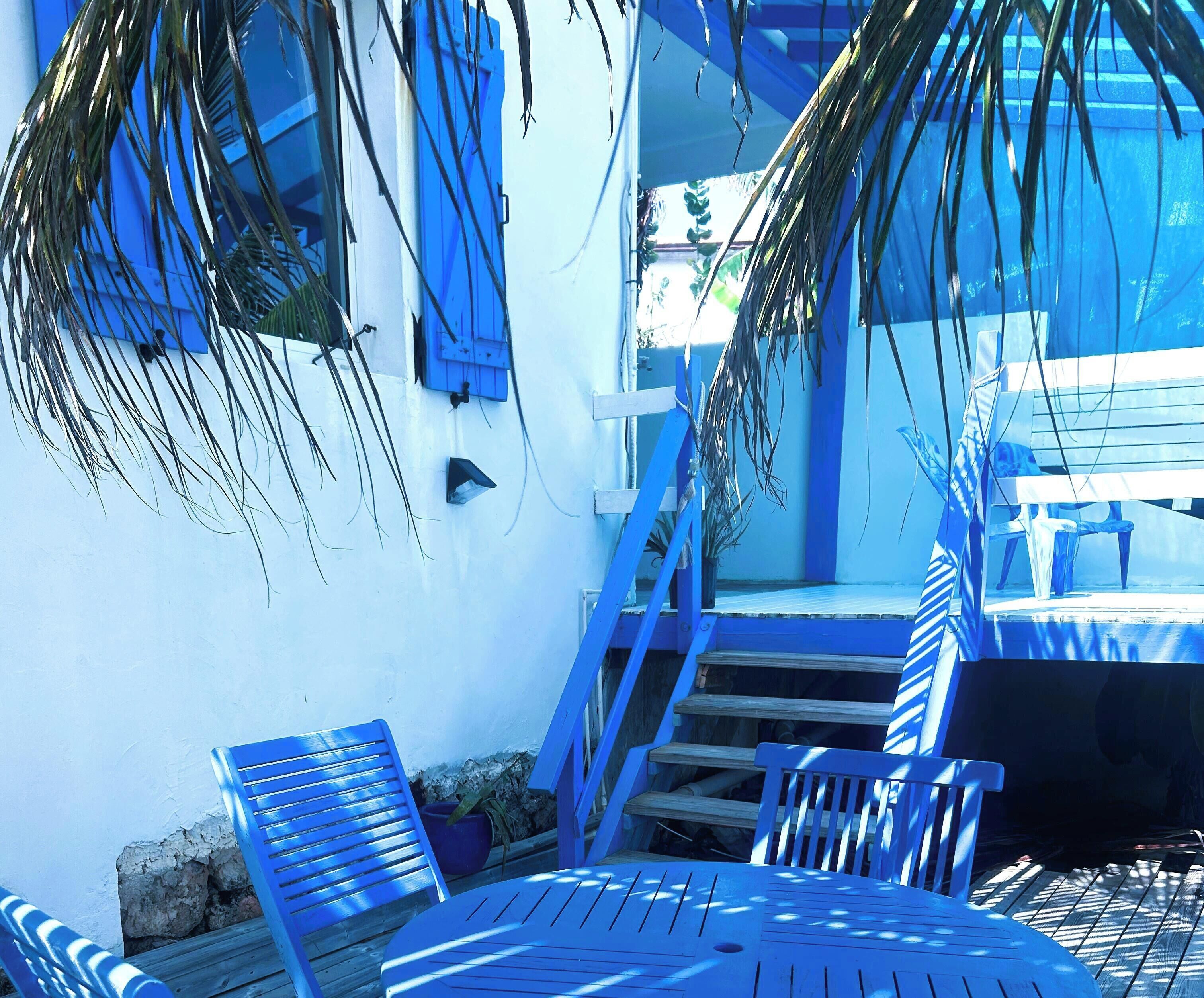 Un'area relax esterna con mobili blu e una scala che conduce a un portico coperto.
