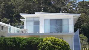 A modern two-story house with large windows, a balcony, and a staircase leading to the upper level. - Beachside Shoal Bay Unit 2 (Shoal Bay)
