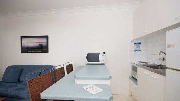 A compact kitchenette with a microwave, sink, and a framed picture of a beach. - Beachside Shoal Bay Unit 2 (Shoal Bay)