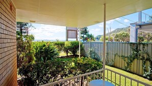 A covered outdoor area with a view of a garden and a wooden fence. - Beachside Shoal Bay Unit 2 (Shoal Bay)